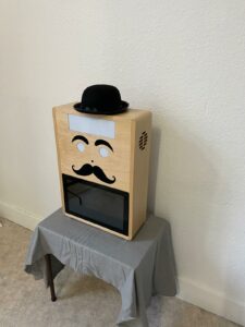 Photobooth Mister Moustache en bois, fabriqué artisanalement, avec chapeau et moustaches, vue de côté droit
